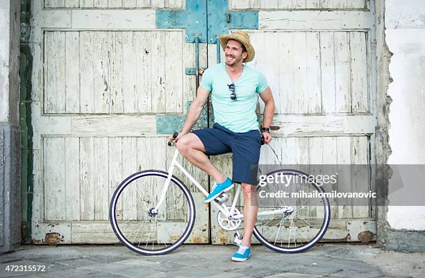 man posing with bicycle - white hat fashion item stockfoto's en -beelden