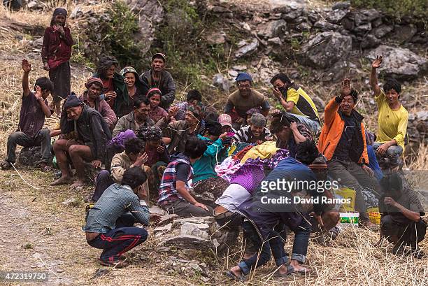 Nepalese villagers wave after collecting aid dropped by an Indian helicopter on May 6, 2015 in Hulchuk, Nepal. A major 7.9 earthquake hit Kathmandu...