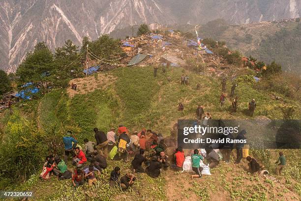 Nepalese villagers take cover after collecting aid dropped by an Indian helicopter on May 6, 2015 in Khanigaun, Nepal. A major 7.9 earthquake hit...