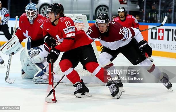 Kevin Fiala of Switzerland and Andris Dzernis of Latvia battle for the puck during the IIHF World Championship group A match between Switzerland and...