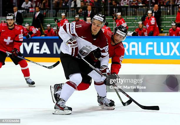 Kevin Romy of Switzerland and Kristaps Sotnieks of Latvia battle for the puck during the IIHF World Championship group A match between Switzerland...