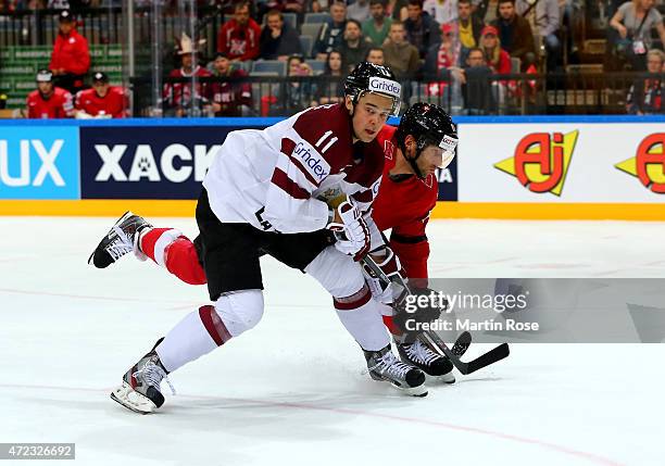 Kevin Romy of Switzerland and Kristaps Sotnieks of Latvia battle for the puck during the IIHF World Championship group A match between Switzerland...