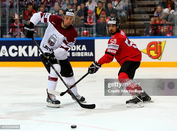 Eric Blum of Switzerland and Armands Berzins of Latvia battle for the puck during the IIHF World Championship group A match between Switzerland and...