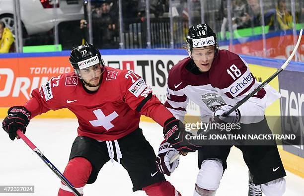 Defender Robin Grossmann of Switzerland and forward Rodrigo Abols of Latvia vie for the puck during the group A preliminary round match Switzerland...