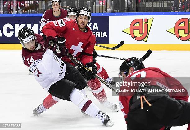 Defender forward Matthias Bieber of Switzerland and forward Mikelis Redlihs of Latvia vie for the puck during the group A preliminary round match...