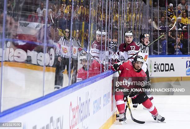 Defender Eric Blum of Switzerland and forward Gunars Skvorcovs of Latvia vie for the puck during the group A preliminary round match Switzerland vs...