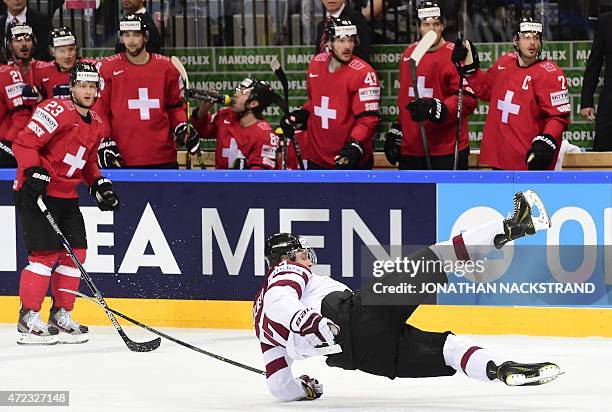 Forward Kaspars Saulietis of Latvia falls after a hit during the group A preliminary round match Switzerland vs Latvia at the 2015 IIHF Ice Hockey...