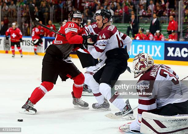Denis Hollenstein of Switzerland and Oskars Cibulskis of Latvia battle for the puck during the IIHF World Championship group A match between...
