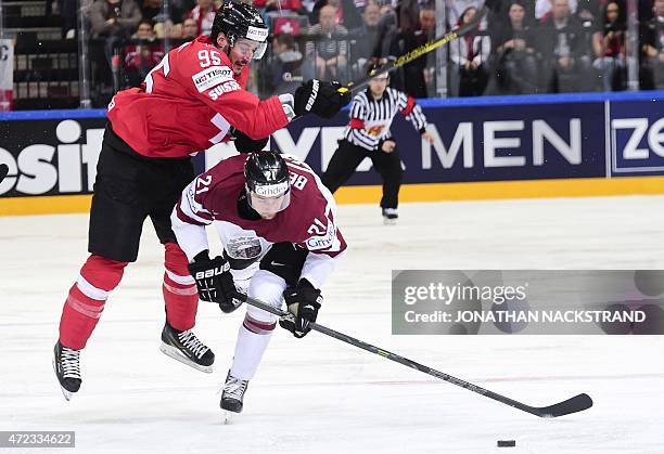 Forward Armands Berzins of Latvia and forward Julian Walker of Switzerland vie for the puck during the group A preliminary round match Switzerland vs...