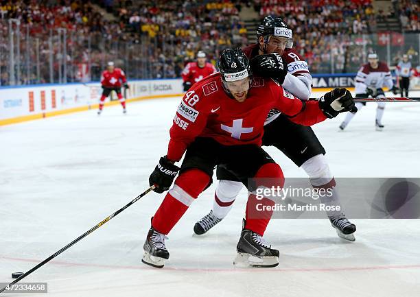 Matthias Bieber of Switzerland and Krisjanis Redlihs of Latvia battle for the puck during the IIHF World Championship group A match between...