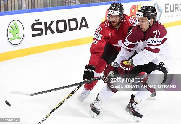 Forward Roberts Bukarts of Latvia and forward Matthias Bieber of Switzerland vie for the puck during the group A preliminary round match Switzerland...