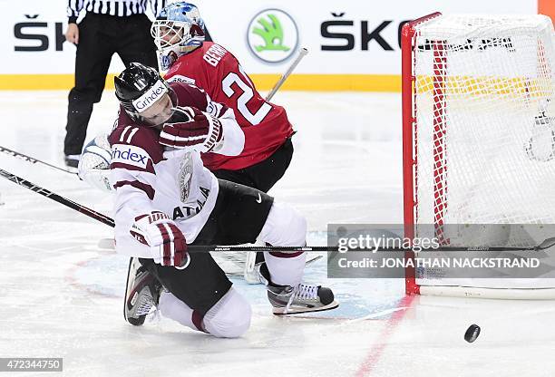 Defender Kristaps Sotnieks of Latvia falls on the ice after getting hit by the puck during the group A preliminary round match Switzerland vs Latvia...