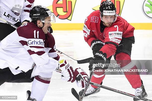 Defender Kristaps Sotnieks of Latvia gets hit by the puck during the group A preliminary round match Switzerland vs Latvia at the 2015 IIHF Ice...