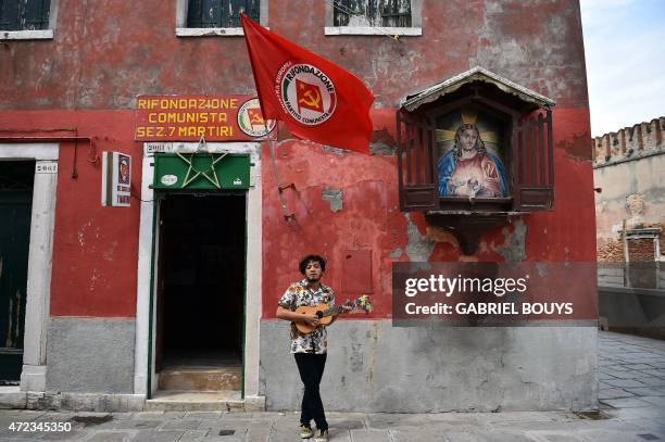 Indonesian musician Ricky Surya Virgana performs in front of the Communist Party 's local office in a street of Venice on May 6, 2015. AFP PHOTO /...