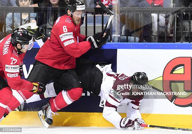 Forward Kaspars Saulietis of Latvia gets hit by defender Timo Helbling of Switzerland during the group A preliminary round match Switzerland vs...