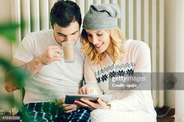 young couple in pajamas using digital tablet. - babygro stock pictures, royalty-free photos & images