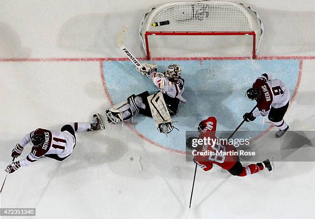 Edgars Masalskis , goaltender of Latvia makes a save on Cody Almond of Switzerland during the IIHF World Championship group A match between...