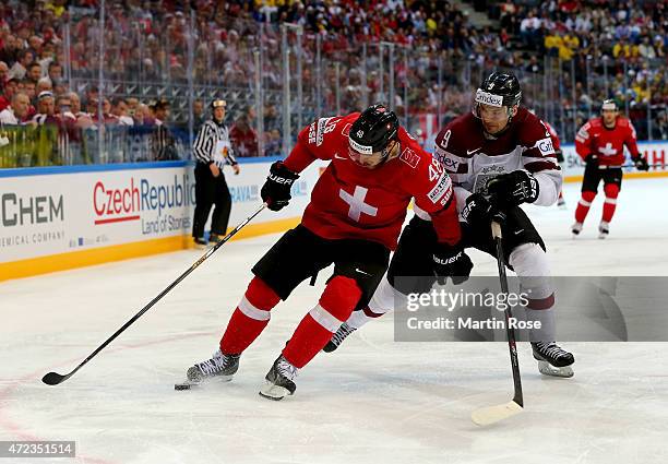 Matthias Bieber of Switzerland and Krisjanis Redlihs of Latvia battle for the puck during the IIHF World Championship group A match between...
