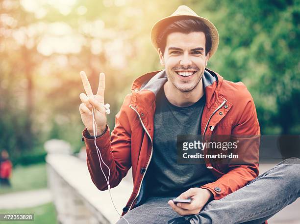hombre sonriente mostrando el cartel de la paz - gesto de victoria fotografías e imágenes de stock
