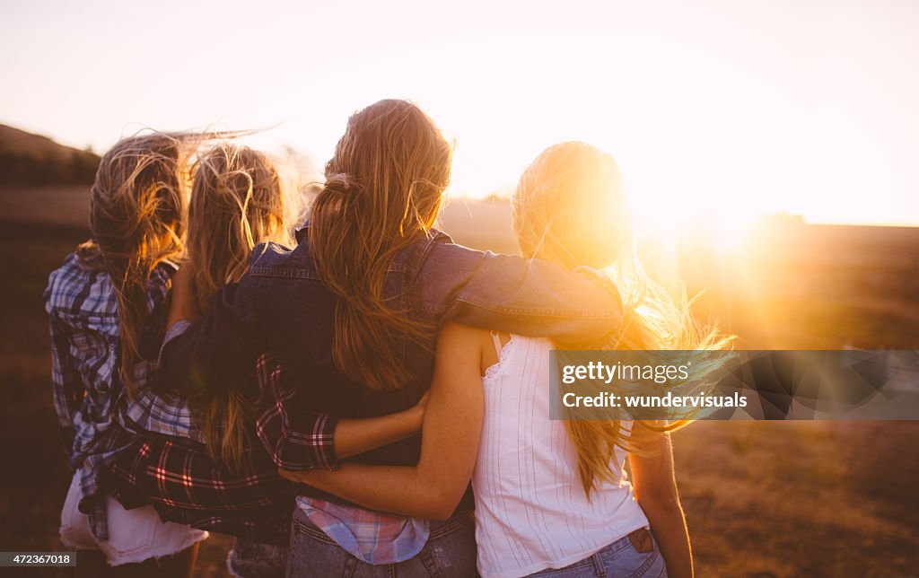 Teen girls facing the sunset with on a summer evening