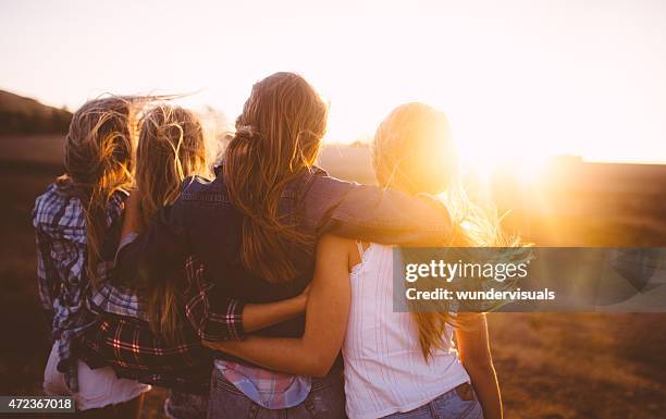 teen girls facing the sunset with on a summer evening - summer friends stockfoto's en -beelden