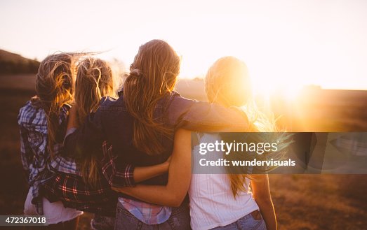 Teen girls facing the sunset with on a summer evening Teen girls facing the sunset with on a summer evening