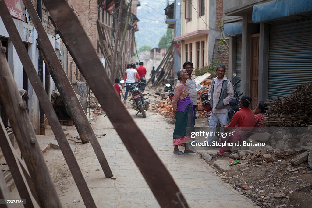 People talk in the street outside damaged buildings...