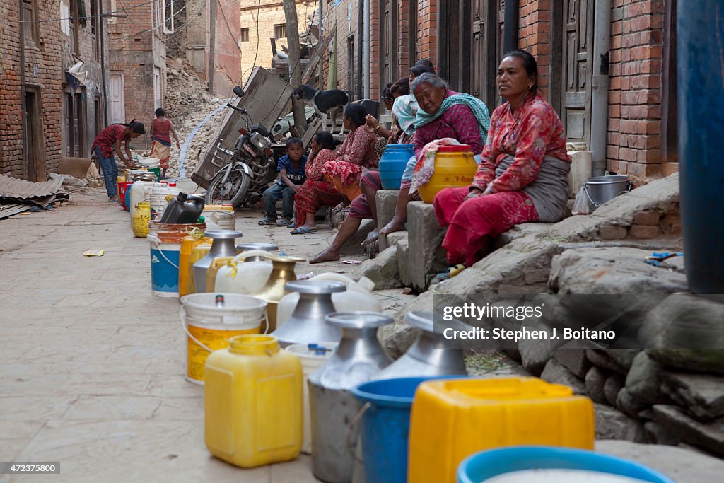 Women wait for water to be pumped to an a neighborhood so...
