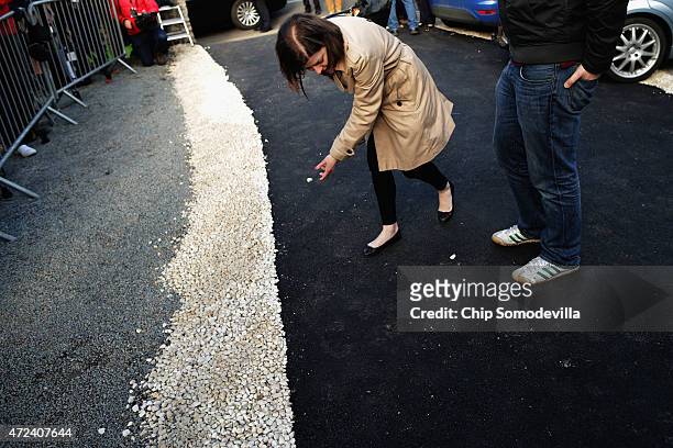 Clearing a path for her boss, a Labour Party campaign staff member moves white stones out of the black asphalt path before Ed Miliband leaves the...
