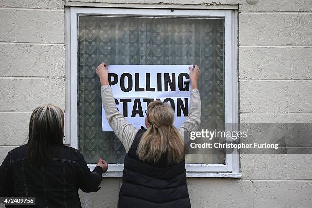 Polling station staff erect a sign as they open the doors for voting and await the arrival of Labour Party leader Ed Miliband and his wife Justine...