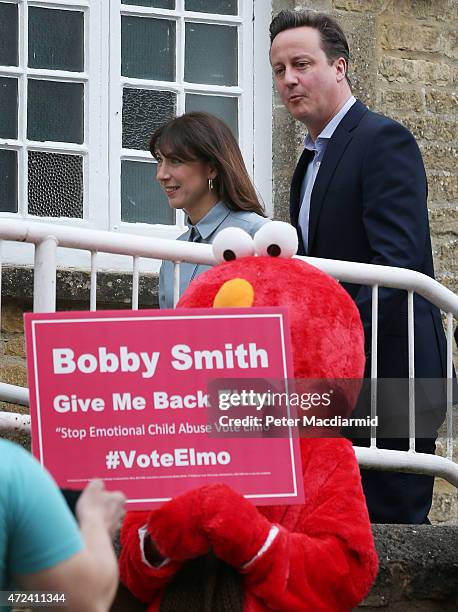 Prime Minister David Cameron and his wife Samantha pass demonstrators as they arrive at a polling station to cast their vote in the general election...