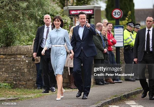 Prime Minister David Cameron points as she walks with his wife Samantha arriving at a polling station to cast their vote in the general election on...