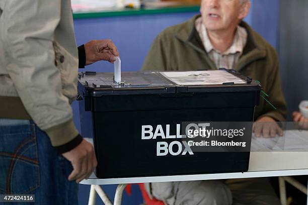 Voter places his vote slip into a ballot box at a polling station located inside a launderette as voting continues in the general election in Oxford,...