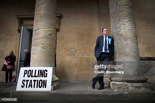 Voter wears a Conservative Party rosette as he stands outside a polling station located inside the town hall as voting continues in the general...