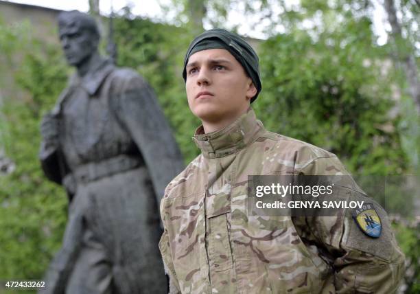 Volunteer of Ukrainian Azov regiment stands next to a Soviet Era memorial in tribute to a World War II soldier, at their base in Kiev on May 7, 2015....