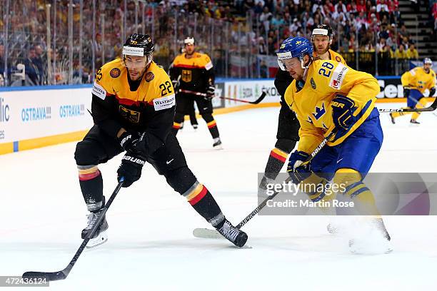 Elias Lindholm of Sweden and Matthias Palchta of Germany battle for the puck during the IIHF World Championship group A match between Sweden and...