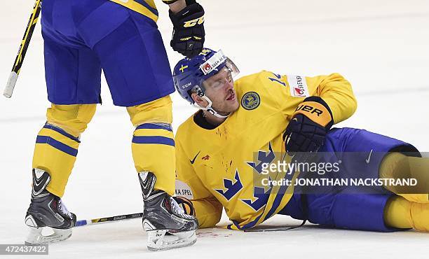 Defender Mattias Ekholm of Sweden lies on the ice with blood running from his nose after a tackle of a German player during the group A preliminary...