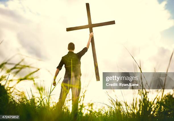 man holding up cross of christ - crucifixion stock pictures, royalty-free photos & images