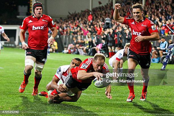 Andy Ellis of the Crusaders dives over to score a try in the tackle of Will Genia of the Reds during the round 13 Super Rugby match between the...