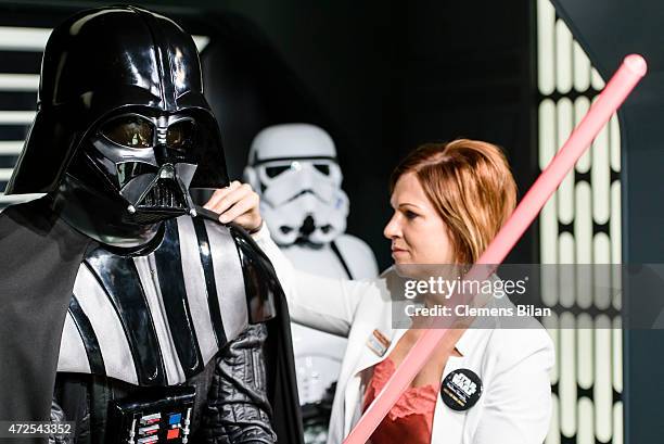 An assistant of the the exhibition poses with a wax figure of the Star Wars characters Darth Vader and a Stormtrooper that are displayed on the...