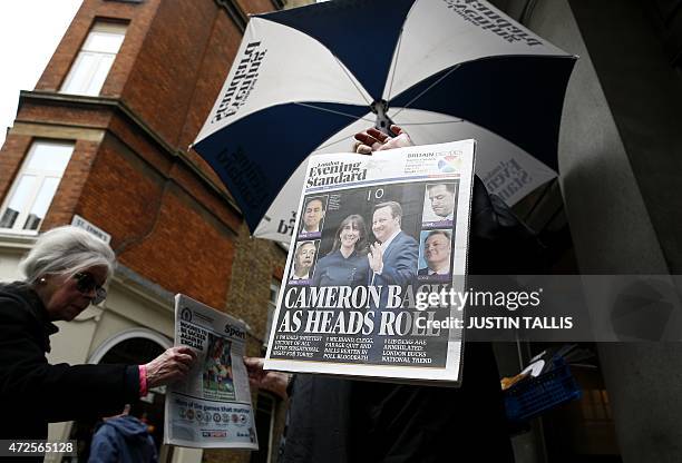Newspaper vendor gives out free newspapers showing election victory for British Prime Minister David Cameron's Conservative Party at a news stand in...