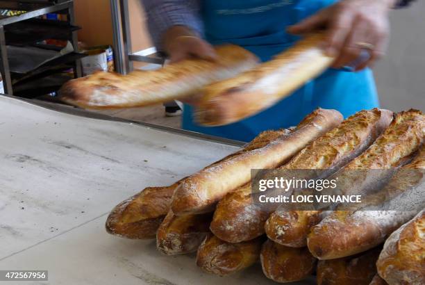 Baker removes bread from an oven during the 20th edition of the bread day on May 8, 2015 in Paris. AFP PHOTO / LOIC VENANCE