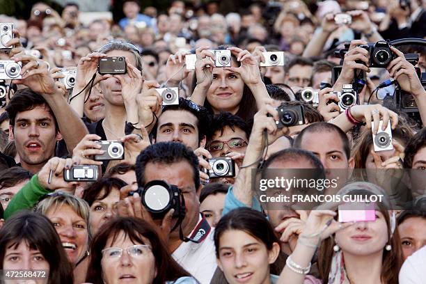 People outside the Festival Palace take photos of guests arriving to attend the screening of US director Steven Spielberg's film 'Indiana Jones and...