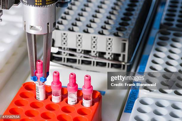 Gripper arm is taking a red capped ampulla out of an orange rack in an ampulla sorting machine.