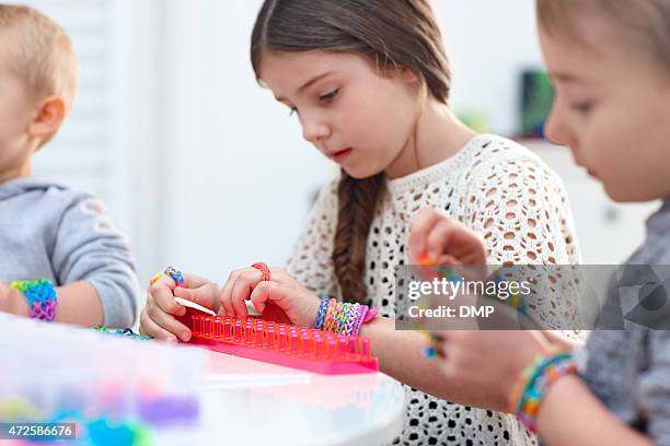 little children together making bracelet from rubber loom bands - bracelet stock pictures, royalty-free photos & images