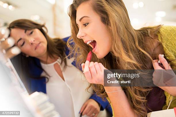 mother and daughter trying lipsticks - cosmetics shopping stock pictures, royalty-free photos & images