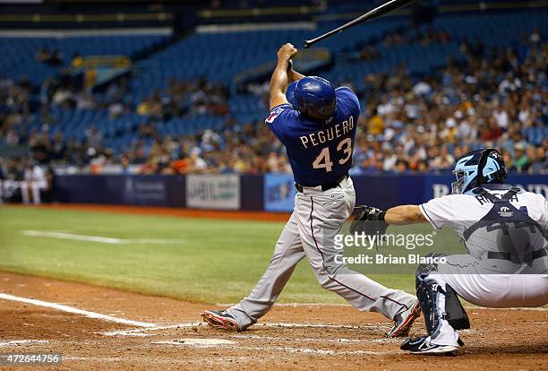 Carlos Peguero of the Texas Rangers loses his grip on his bat as he strikes out swinging in front of catcher Rene Rivera of the Tampa Bay Rays to end...