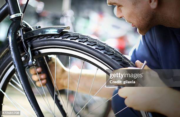 bike mechanic repairing a wheel - bicycle repair stock pictures, royalty-free photos & images