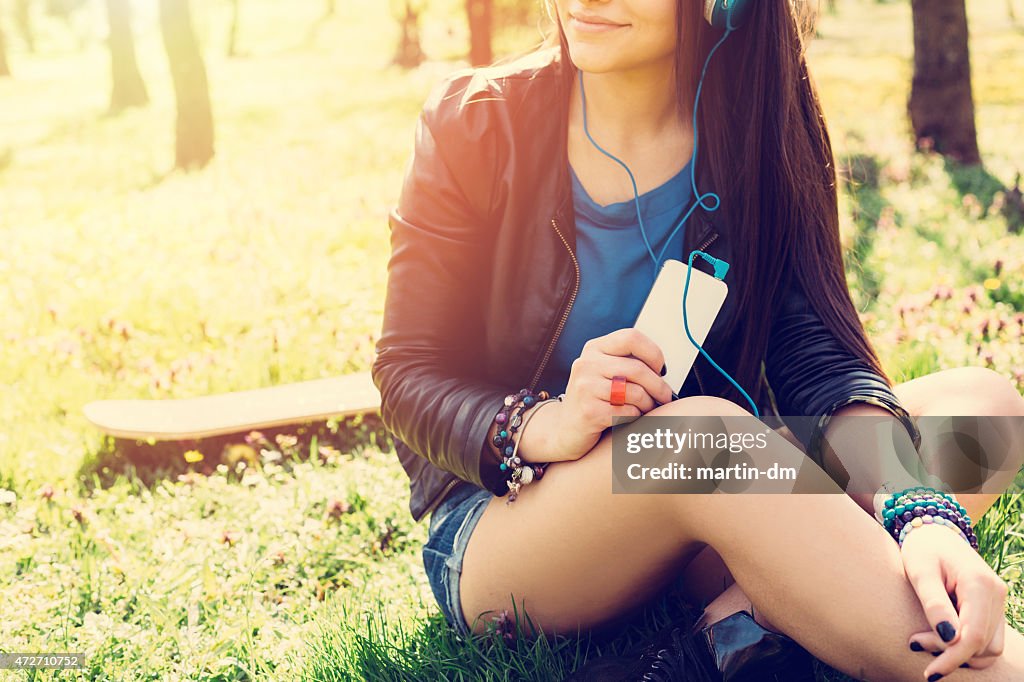 Teenage girl with smartphone sitting in the grass