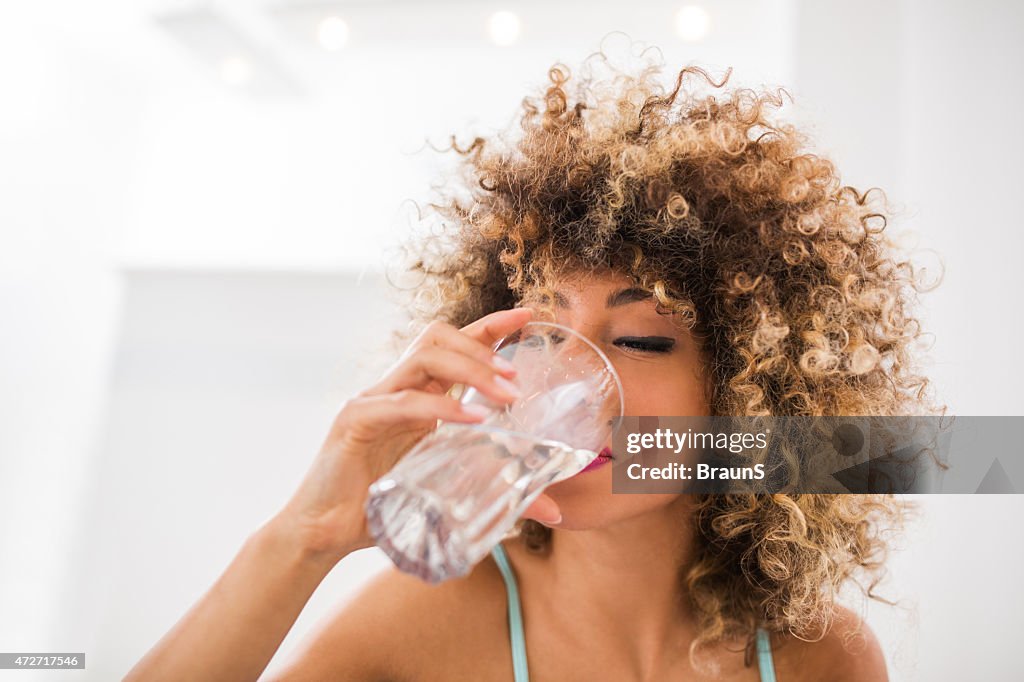 Thirsty African American woman drinking water.